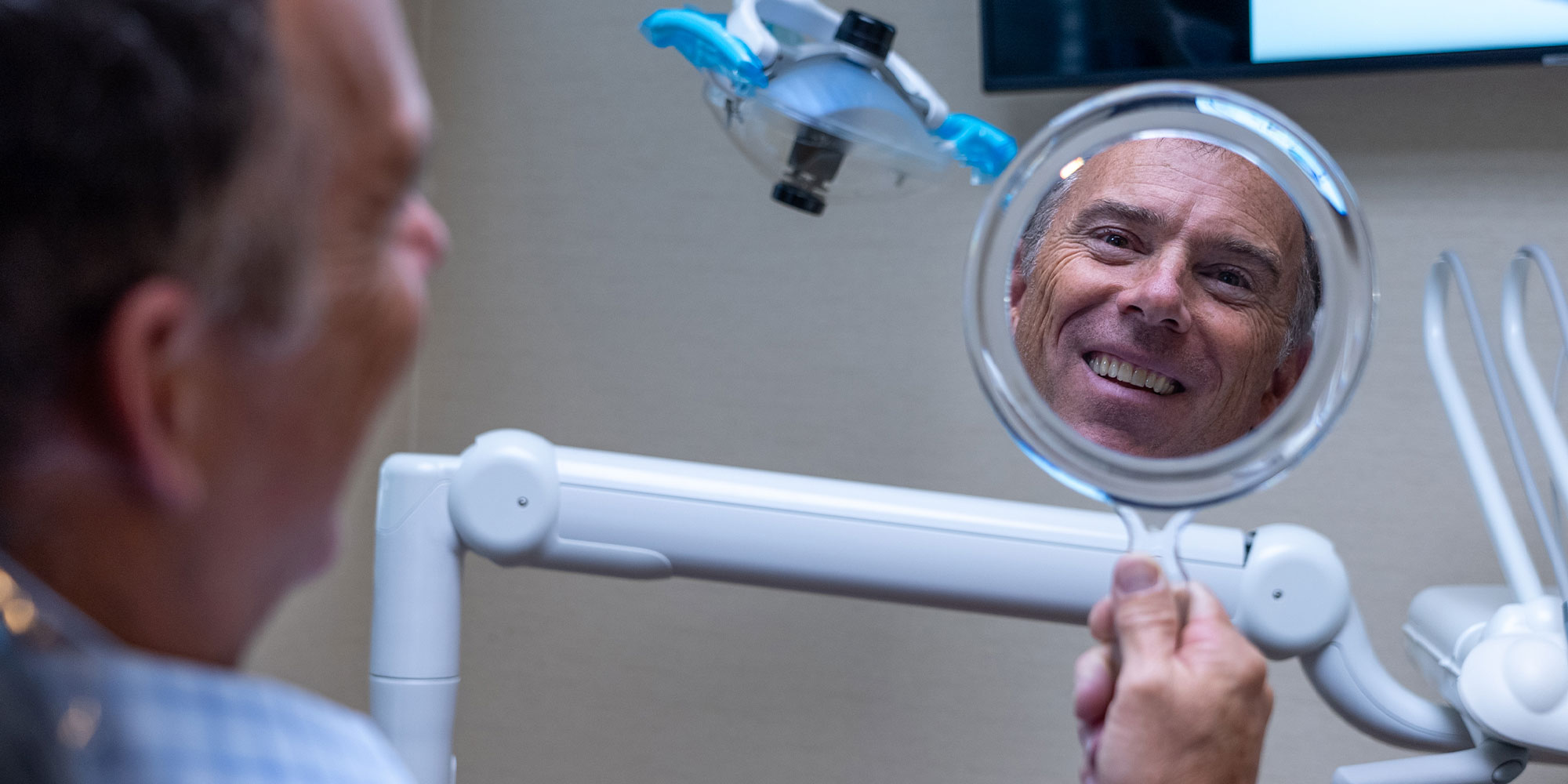 patient looking at their new smile after oral surgery